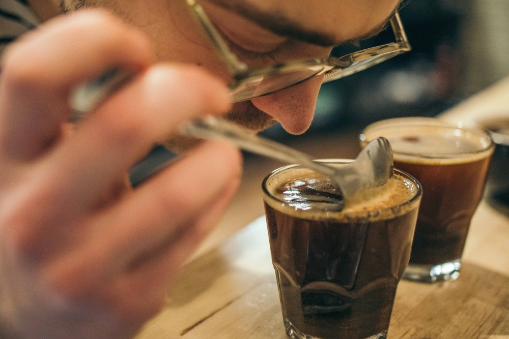 Degustátor zkoumá aroma kávy během cuppingu v pražírně